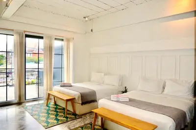 a hotel room with two beds and a window at Old Town Heritage Lofts Bangkok in Bangkok
