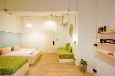 a room with two beds and a chair in it at Old Town Heritage Lofts Bangkok in Bangkok