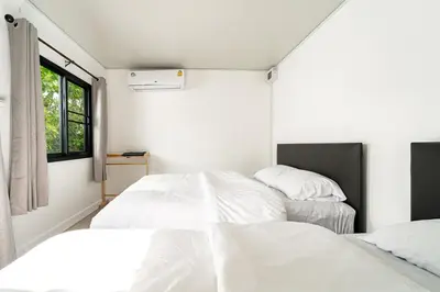 two beds in a white room with a window at The Lodge Bangkok Poolvilla in Sathani Khlong Tan