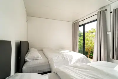 a bedroom with three beds and a window at The Lodge Bangkok Poolvilla in Sathani Khlong Tan