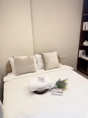 a white bed with two towels and flowers on it at 2 Bed 2 Bath Phrom Phong BTS in Bangkok