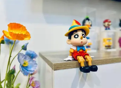 a toy figurine sitting on a counter next to flowers at Tiny Cozy Room - Wat Arun in Bangkok