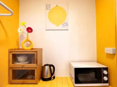 a microwave sitting on top of a wooden cabinet at Tiny Cozy Room - Wat Arun in Bangkok