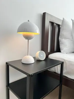 a lamp and a clock on a table next to a bed at Wonderful Stay BTS Ratchayothin in Bangkok