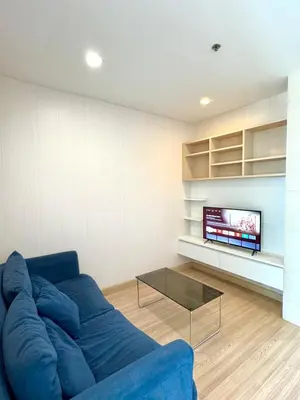 a living room with a blue couch and a tv at Super City View Room, Swimming Pool,Gym,150m walk to BTS in Bangkok