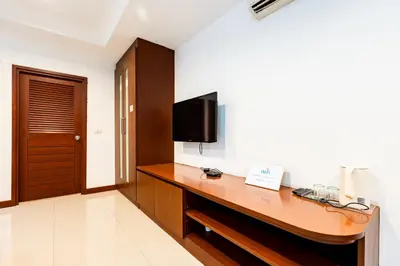 a hotel room with a desk with a tv on the wall at XX YON INN - Sukhumvit 4 BTS NANA in Bangkok
