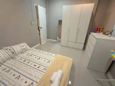 a room with a bed and a kitchen with white cabinets at Privacy House in Ban Bang Phai