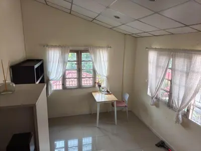 a room with a table and two windows and a desk at Privacy House in Ban Bang Phai
