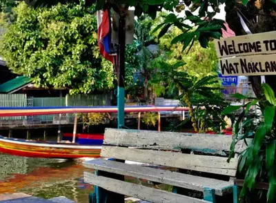 a wooden bench next to a boat in the water at Lamduan house whole House - 3BR - Experience temple and canal life in Bangkok