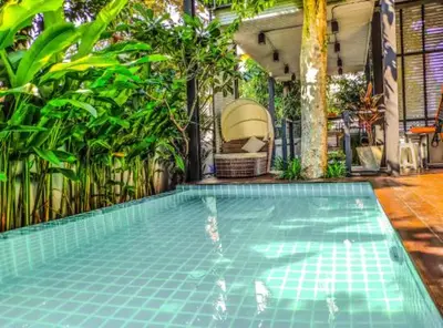 a swimming pool with a chair and some plants at Garden and pool Villa bangkok in Bang O