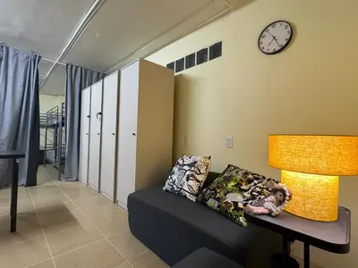 a living room with a couch and a clock on the wall at NIJ Lady dorm in Bangkok