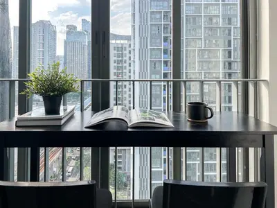 a table with a book and a coffee mug on it at Tranquil Apt 2 BR - Ultra Fast Wifi - BTS On Nut in Bangkok