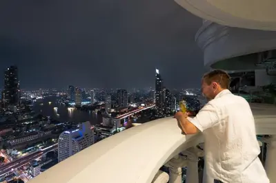 a man taking a picture of a city at night at Bangrak HANGOVER 2 Central River Station in Bangkok