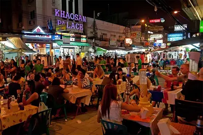 a crowd of people sitting at tables in a street at night at xx GO INN Khaosan BKK - โกอินน์ ข้าวสาร in Bang Bua Thong Railway Station