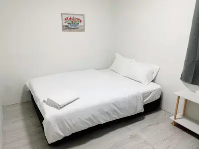 a bed with white sheets and a picture on the wall at xx GO INN Siriraj BKK โกอินน์ ศิริราช in Bangkok Noi