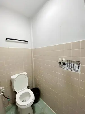 a bathroom with a toilet and a tiled wall at xx GO INN Siriraj BKK โกอินน์ ศิริราช in Bangkok Noi