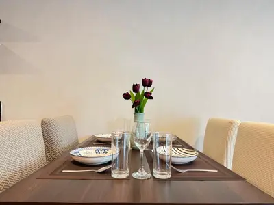a table with glasses and a vase of flowers on it at Central Living Ploenchit in Bang Kapi