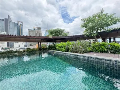 a large swimming pool with a bridge in a city at Central Living Ploenchit in Bang Kapi
