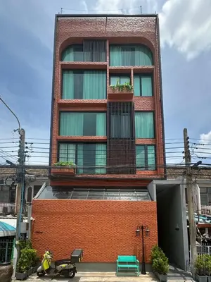 a tall red brick building with windows and a scooter parked in front at Thai Loft \u6cf0\u95a3 in Bangkok