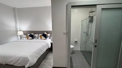 a bedroom with a bed and a shower and a toilet at The Kite Hotel Bangkok in Bangkok