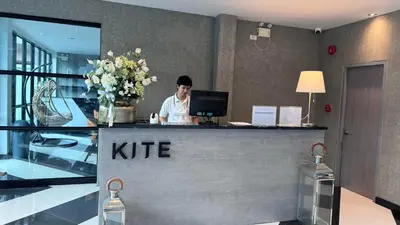 a man sitting at a k rite counter in a lobby at The Kite Hotel Bangkok in Bangkok