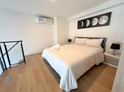 a bedroom with a white bed with a stuffed animal on it at BTS onnut loft quiet room Netflix Rooftop bar in Bangkok