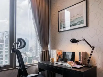a desk with a laptop and a lamp in front of a window at Modern High-Rise 1BR - Ultra Fast Wifi - Sathorn in Bangkok