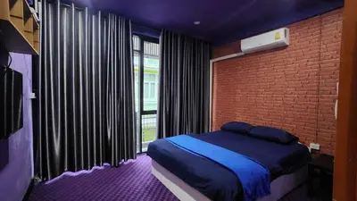 a bedroom with a bed and a brick wall at Ber Ben House in Bang Su