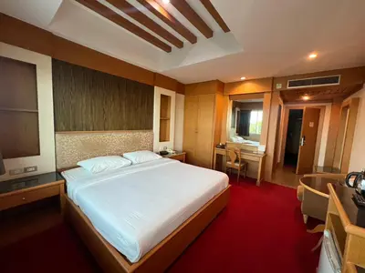 a bedroom with a large bed and a desk at The Rich Hotel Rama 5 in Ban Bang Phai