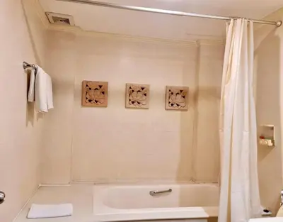 a bathroom with a tub and a shower curtain at The Rich Hotel Rama 5 in Ban Bang Phai