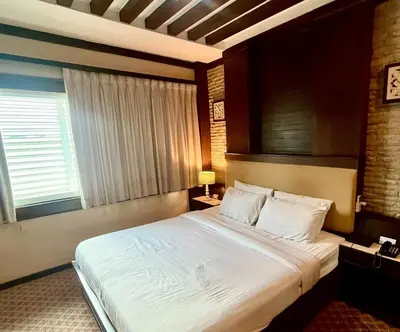 a bedroom with a large bed and a window at The Rich Hotel Rama 5 in Ban Bang Phai