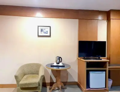 a room with a tv and a table and a chair at The Rich Hotel Rama 5 in Ban Bang Phai