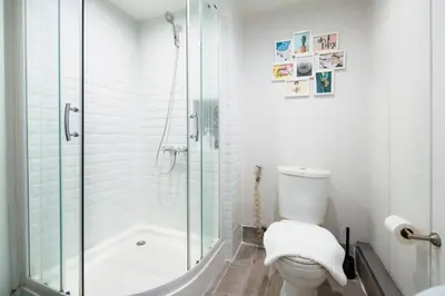 a white bathroom with a shower and a toilet at Non Inn Entire Historic 5 Bedroom Riverside Shophouse near ICONSIAM for Families and Groups in Bang Rak