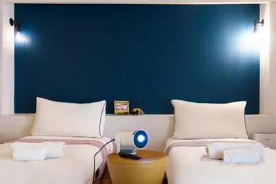 two beds in a room with a blue wall at Non Inn Entire Historic 5 Bedroom Riverside Shophouse near ICONSIAM for Families and Groups in Bang Rak