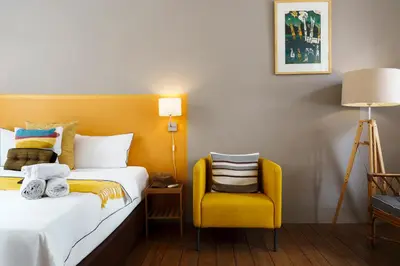 a hotel room with a bed and a yellow chair at Non Inn Entire Historic 5 Bedroom Riverside Shophouse near ICONSIAM for Families and Groups in Bang Rak