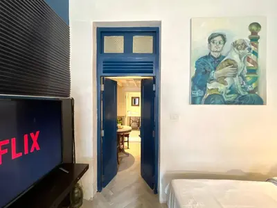 a room with a tv and a painting on the wall at Non Inn The Barber King and Twin Rooms with Vintage Charm and Unique Design near Riverside and ICONSIAM in Bang Rak