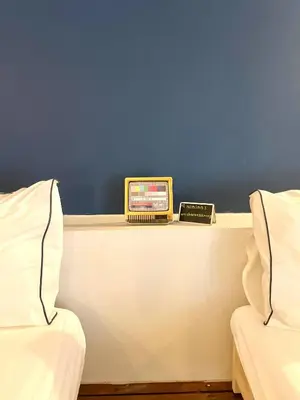 a table with a clock on it next to two beds at Non Inn The Barber King and Twin Rooms with Vintage Charm and Unique Design near Riverside and ICONSIAM in Bang Rak