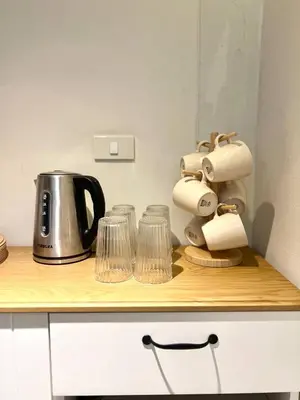 a counter with a coffee maker and glasses on it at Non Inn The Barber King and Twin Rooms with Vintage Charm and Unique Design near Riverside and ICONSIAM in Bang Rak