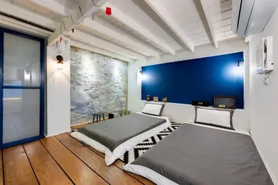 two beds in a room with a blue wall at Non Inn The Barber King and Twin Rooms with Vintage Charm and Unique Design near Riverside and ICONSIAM in Bang Rak