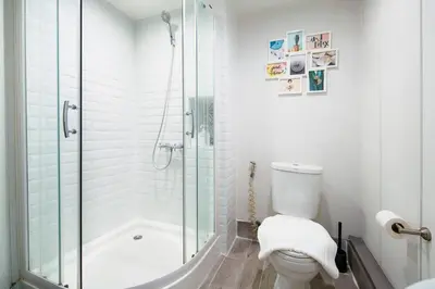 a white bathroom with a shower and a toilet at Non Inn The Diamond Artisan King and Twin Rooms with Private Coffee Station and InnerCourt Quiet View near Riverside and ICONSIAM in Bang Rak