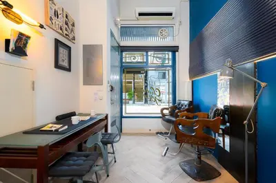 a room with a desk and chairs and a window at Non Inn The Post and Barber 3 Bedroom Riverside Shophouse with King and Twin Rooms in Bang Rak