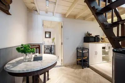 a room with a table and a kitchen with a staircase at Non Inn The Post and Barber 3 Bedroom Riverside Shophouse with King and Twin Rooms in Bang Rak
