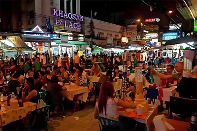 a crowd of people sitting at tables in a street at night at XX The Hidden Khaosan - เดอะ ฮิดเด้น ข้าวสาร รามบุตรี 7 in Bang Bua Thong Railway Station