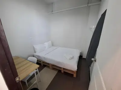 a small bedroom with a bed and a table at XX The Hidden Khaosan - เดอะ ฮิดเด้น ข้าวสาร รามบุตรี 7 in Bang Bua Thong Railway Station