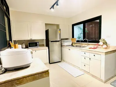 a kitchen with white cabinets and a stainless steel refrigerator at Private Pool Villas Sukhumvit 26 Near BTS Phrom Phong and EmSphere in Bangkok