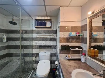 a bathroom with a toilet and a shower and a sink at Kuma House Sukhumvit in Bangkok