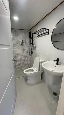 a white bathroom with a toilet and a sink at Baan Yard - More than 5 nights stay in Bangkok