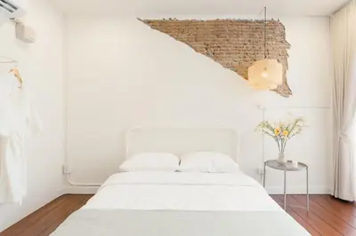 a bedroom with a white bed and a brick wall at House of Patcha เรือลพัชชา Hostel share bathroom in Bangkok