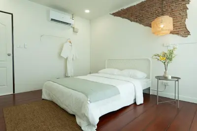 a white bedroom with a bed and a brick wall at House of Patcha เรือลพัชชา Hostel share bathroom in Bangkok