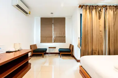 a bedroom with a bed and two chairs and a desk at XX YON INN Sukhumvit 4 Bangkok - BTS Nana in Bang Kapi